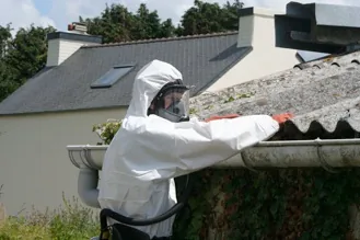 Opérateur en combinaison de protection lors d'une dépose de toiture en fibrociment